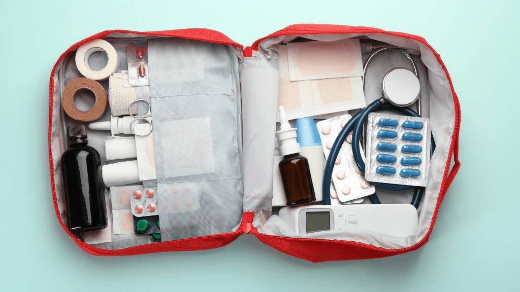 Eine vollständig bestückte, rote Notfalltasche liegt geöffnet auf dem Boden. Sichtbar sind Pflaster, Bandagen, Desinfektionsmittel und weitere medizinische Geräte.