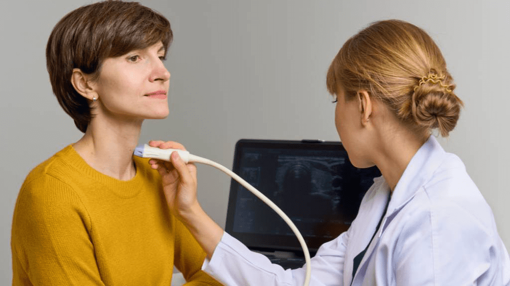 Arzt untersucht mittels Tastuntersuchung die sichtbar vergrößerte Schilddrüse einer Patientin.
