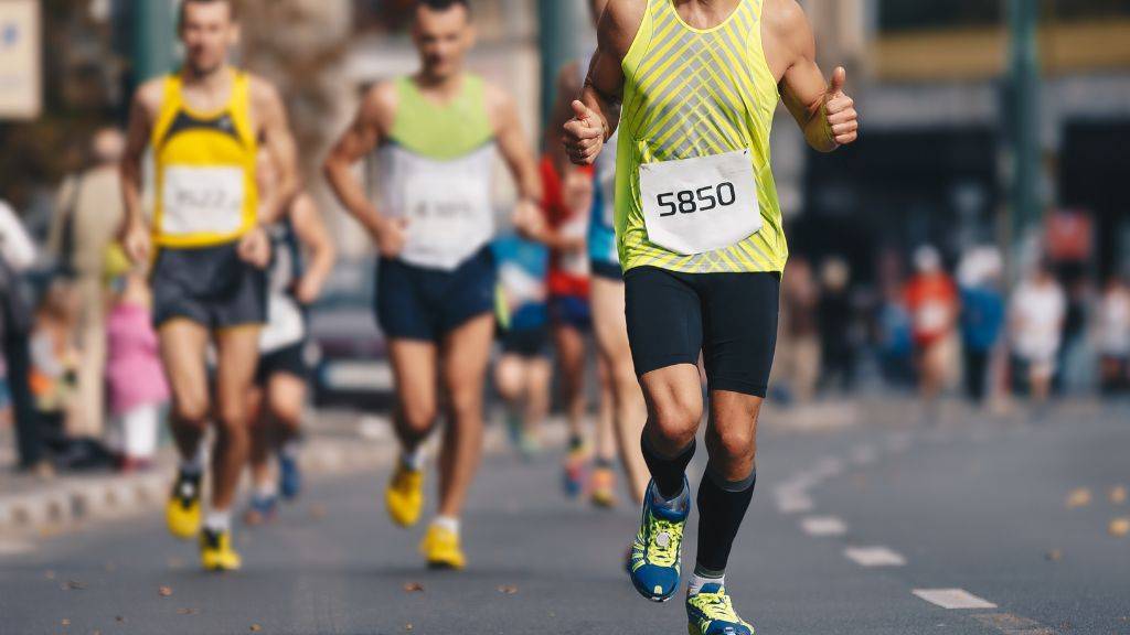 Eine Gruppe Menschen mit Startnummern läuft einen Marathon auf einer Straße