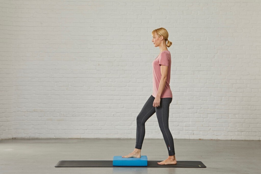 Eine Frau tritt mit einem Fuß auf ein Balance-Pad.