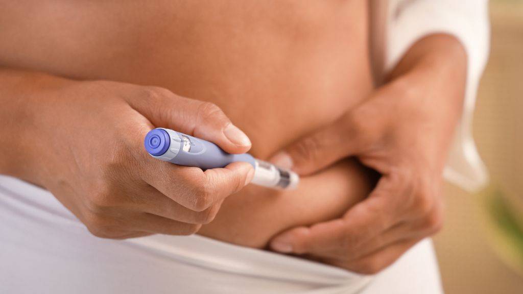 Eine Person gibt sich eine "Abnehmspritze" in die Bauchfalte.