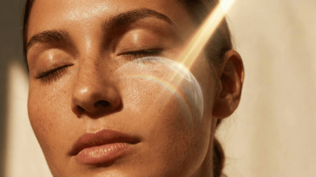 Frau mit geschlossenen Augen im warmen Sonnenlicht – Symbolbild für strahlende Haut, Glow-Effekt und ästhetische Hautbehandlungen vor dem Sommer mit Fokus auf Pflege und Sonnenschutz.