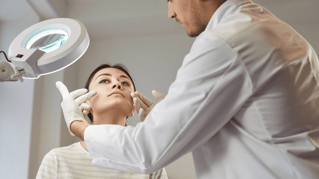Facharzt für Plastische und Ästhetische Chirurgie berät Patientin bei Gesichtsbehandlung und untersucht Gesichtspartien für natürliche ästhetische Ergebnisse.