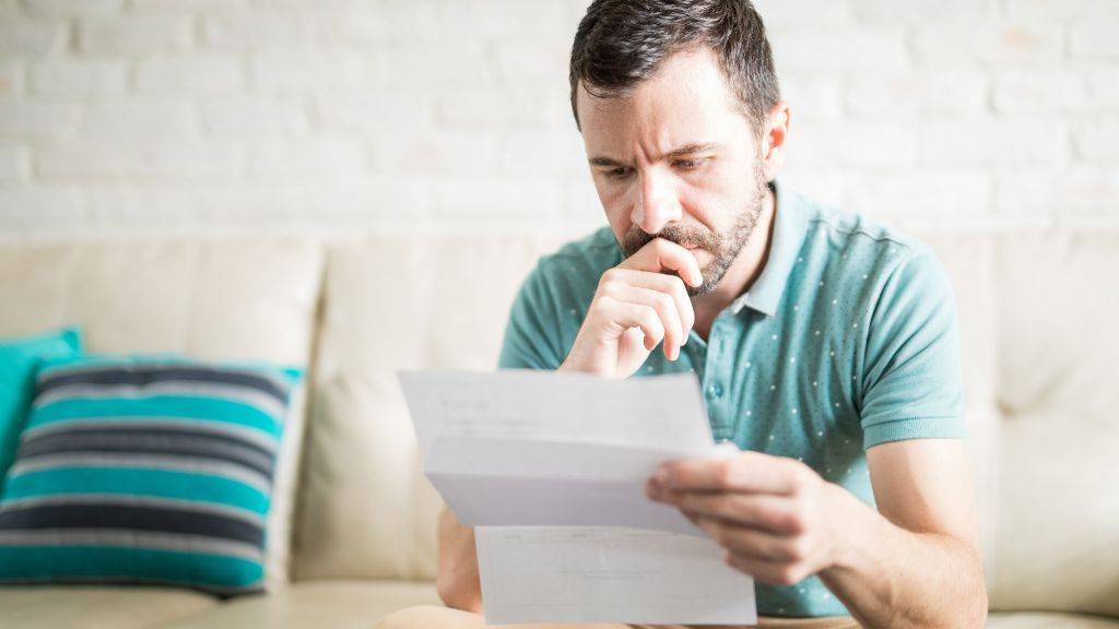 Ein Mann sitzt auf dem Sofa uns liest einen Brief