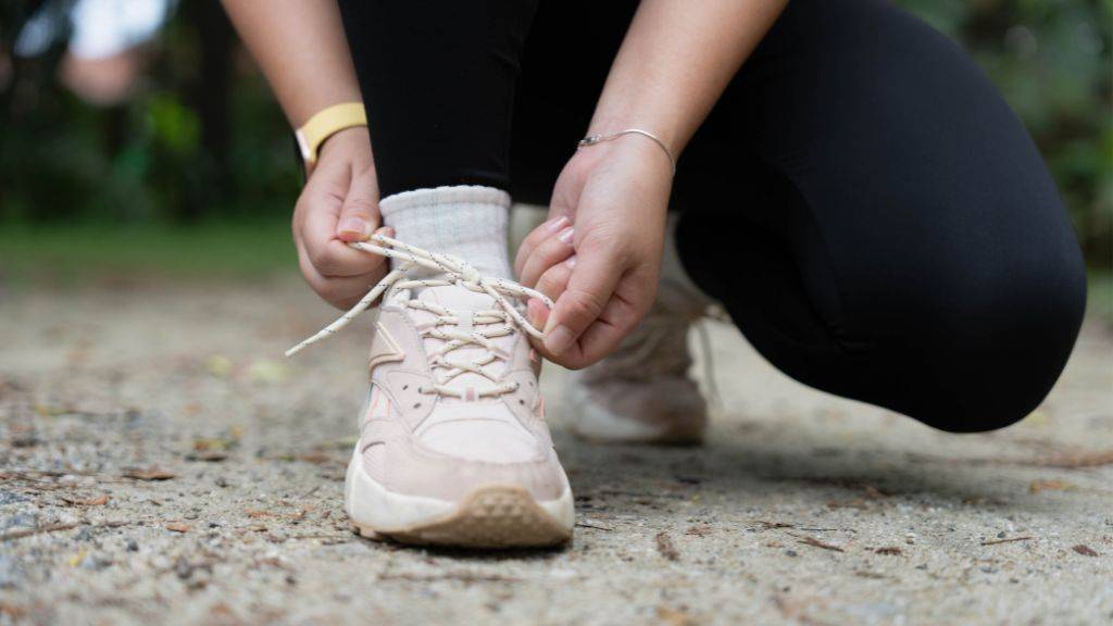 Eine Person bindet sich den Schuh. Symbol für Training oder Start eines Rennens.