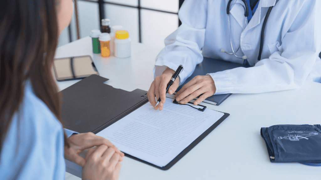 Ärztin oder Arzt bespricht mit einer Patientin einen Behandlungsplan und zeigt auf ein Dokument. Das Arztgespräch ist ein wichtiger Bestandteil der Therapie chronischer Schmerzen.