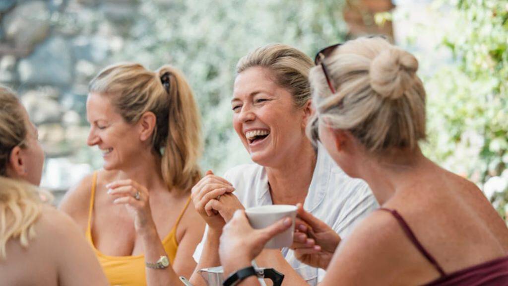 Frauen zwischen 35 und 45 sitzen zusammen und lachen.