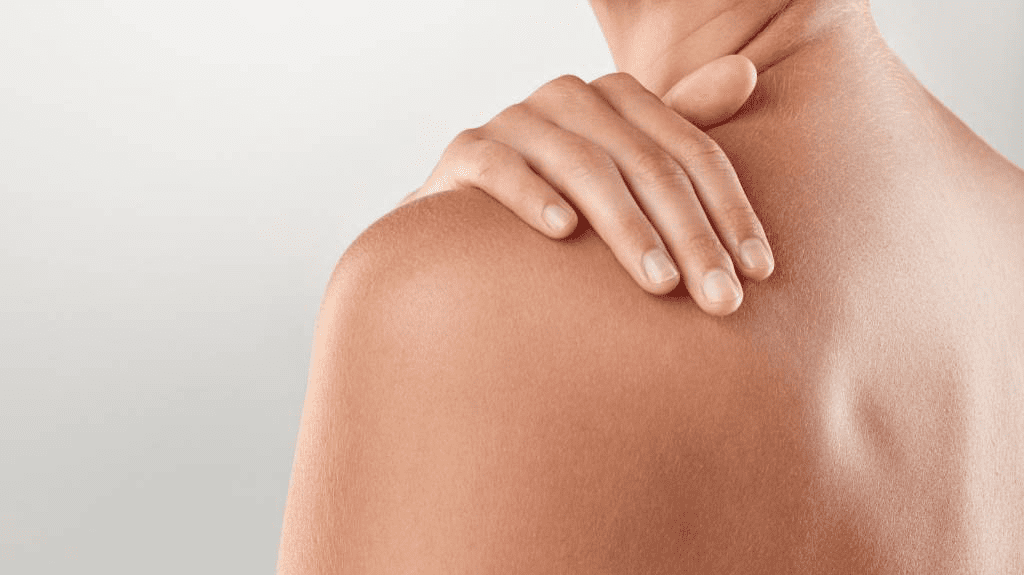 Hand liegt sanft auf einer gepflegten, natürlichen Schulter einer Person mit gesunder Haut.