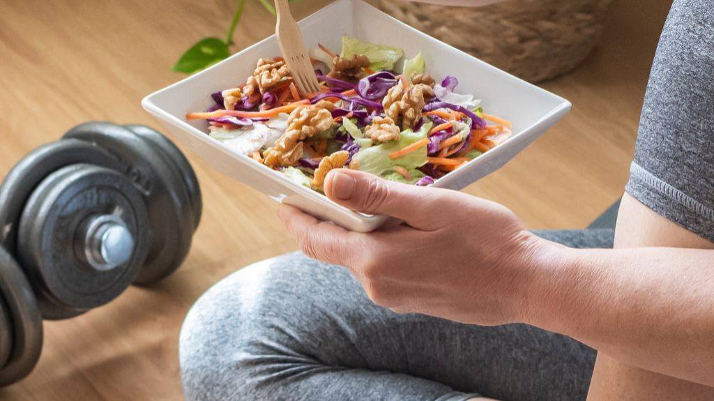 Nach dem Sport isst eine Frau eine proteinreiche Bowl.