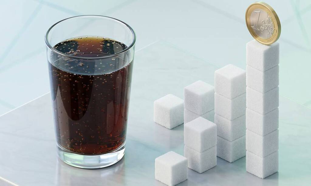 Ein klares Glas, gefüllt mit dunkler, sprudelnder Cola, steht neben einem ansteigenden Balkendiagramm aus gestapelten weißen Zuckerwürfeln. Eine Ein-Euro-Münze balanciert auf dem höchsten Zuckerstapel ganz rechts.